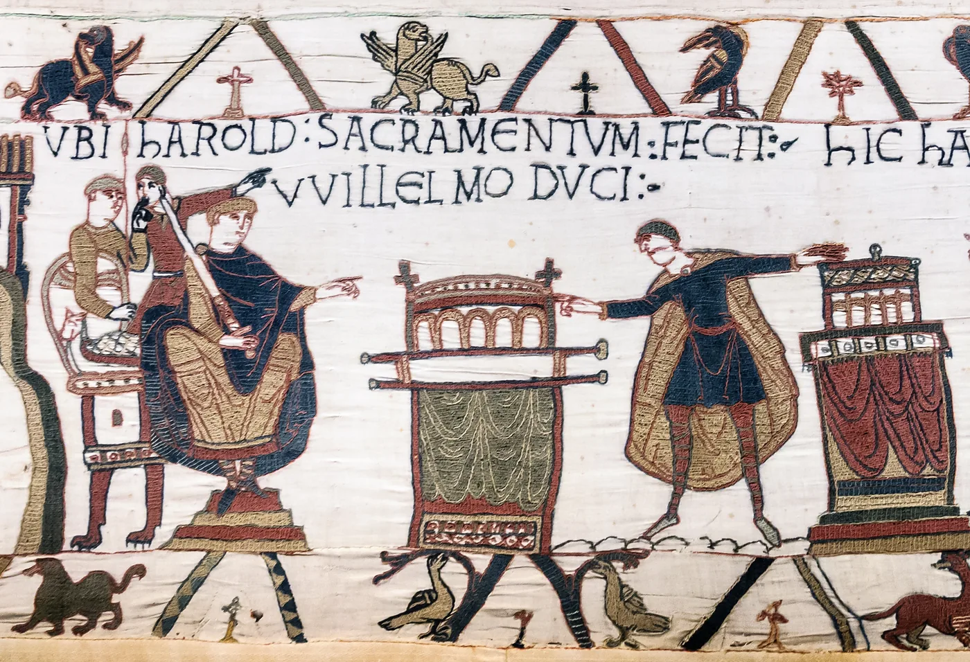 Harold, les mains posées sur deux reliquaires, prête serment devant Guillaume assis. L’inscription latine dit : « ici Harold fit serment au duc Guillaume » (Tapisserie de Bayeux, scène 23).